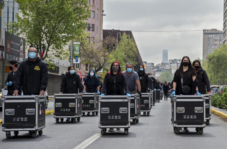 Membros da Associação de Artes e Espetáculos (AGTAE) marcham empurrando caixas com luzes e fios durante um protesto exigindo apoio do governo do presidente chileno Sebastian Pinera para enfrentar a crise provocada pela pandemia. Foto Martin Bernetti/AFP