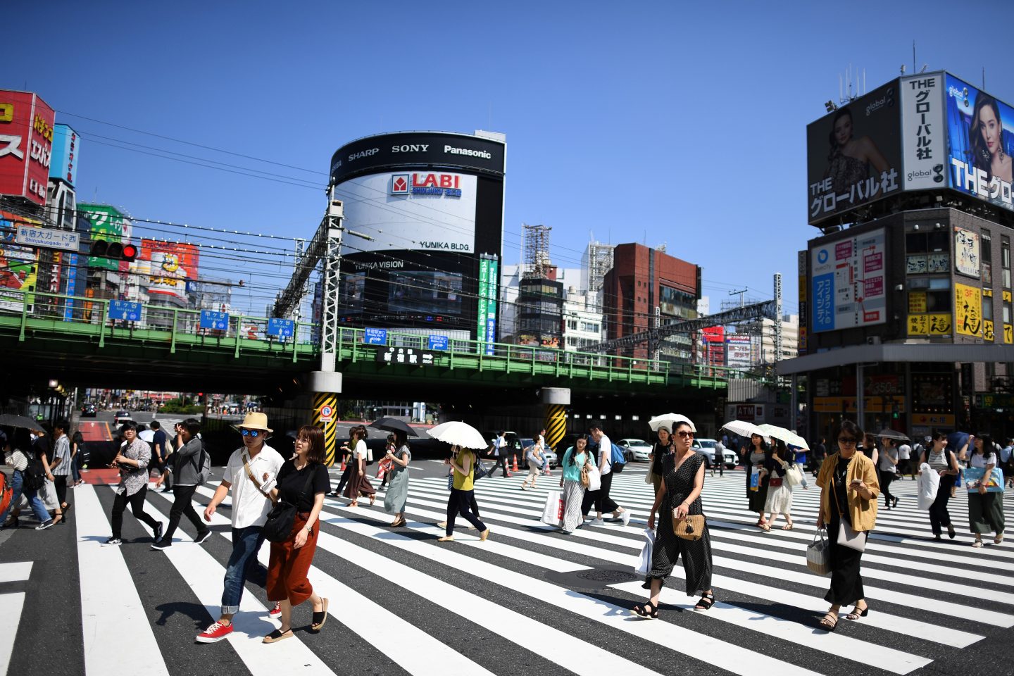 Moradores de Tóquio usam sombrinhas para se proteger de sol no último verão: diferença das ilhas de calor para pontos mais frescos da capital japonesa chega a cinco graus centígrados (Foto: Charly Triballeau/AFP)