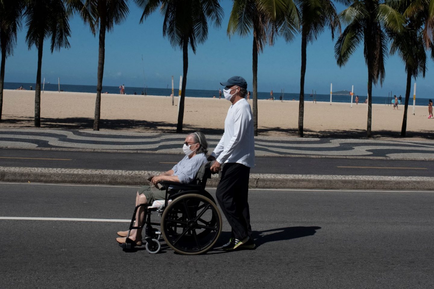Idosa conduzida por acompanhante na praia de Copacabana: estudo da Fiocruz indica aumento no número de idosos que faleceu fora de hospitais, em sua residência ou em abrigos - 78% no município e 54% no estado (Foto: Fábio Teixeira/Nur Photo/AFP)