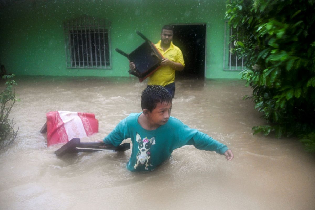 Pai e filho resgatam móveis de casa no norte da Guatemala na passagem do Eta: furacões mais frequentes e mais destrutivos com aquecimento global (Foto: Johann Ordoñez/AFP)