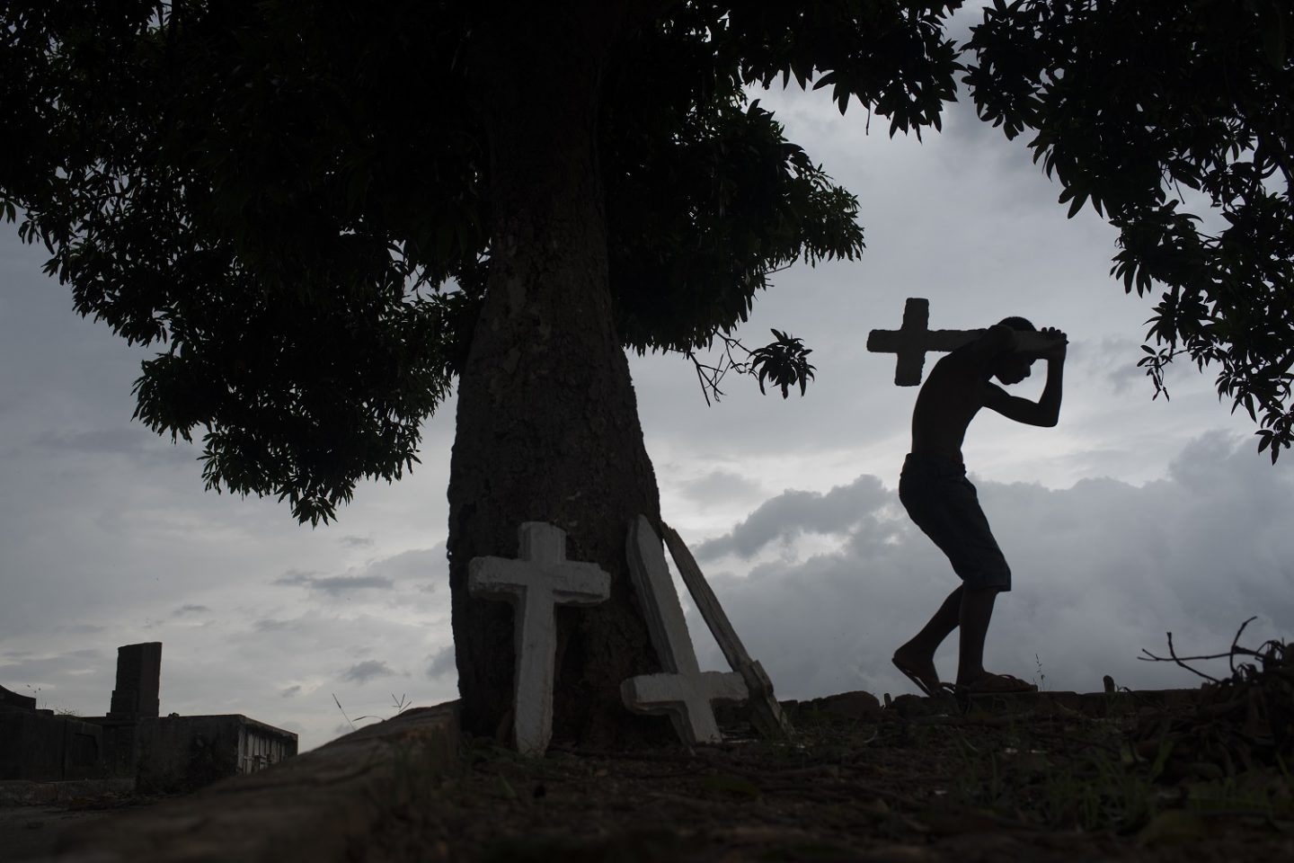 Jovem trabalha em um cemitério do Rio, pintando cruzes, limpando túmulos e correndo risco de contaminação. Foto Fabio Teixeira/NurPhoto - Julho de 2020