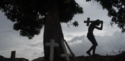 Jovem trabalha em um cemitério do Rio, pintando cruzes, limpando túmulos e correndo risco de contaminação. Foto Fabio Teixeira/NurPhoto - Julho de 2020