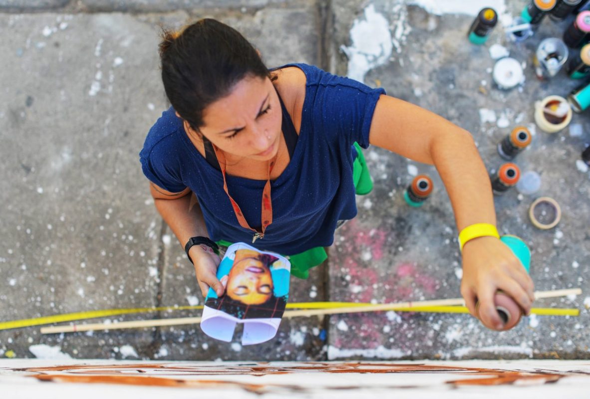 A grafiteira e artista plástica Dolores em ação antes da pandemia: das ruas para trabalhos em casa e cursos virtuais (Foto: Divulgação)