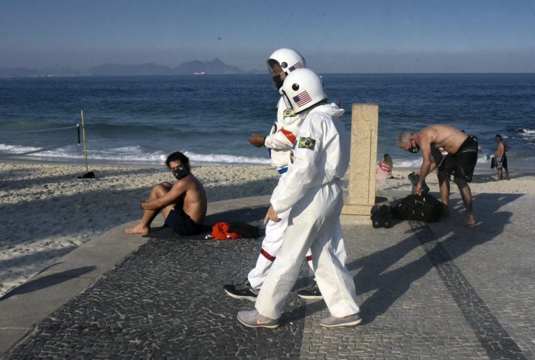 Casal de idosos caminha em Ipanema, no Rio, vestido de astronauta, na semana em que o Brasil bateu o recorde de mortes e casos (Foto: Fabio Teixeira/Andalou/AFP)