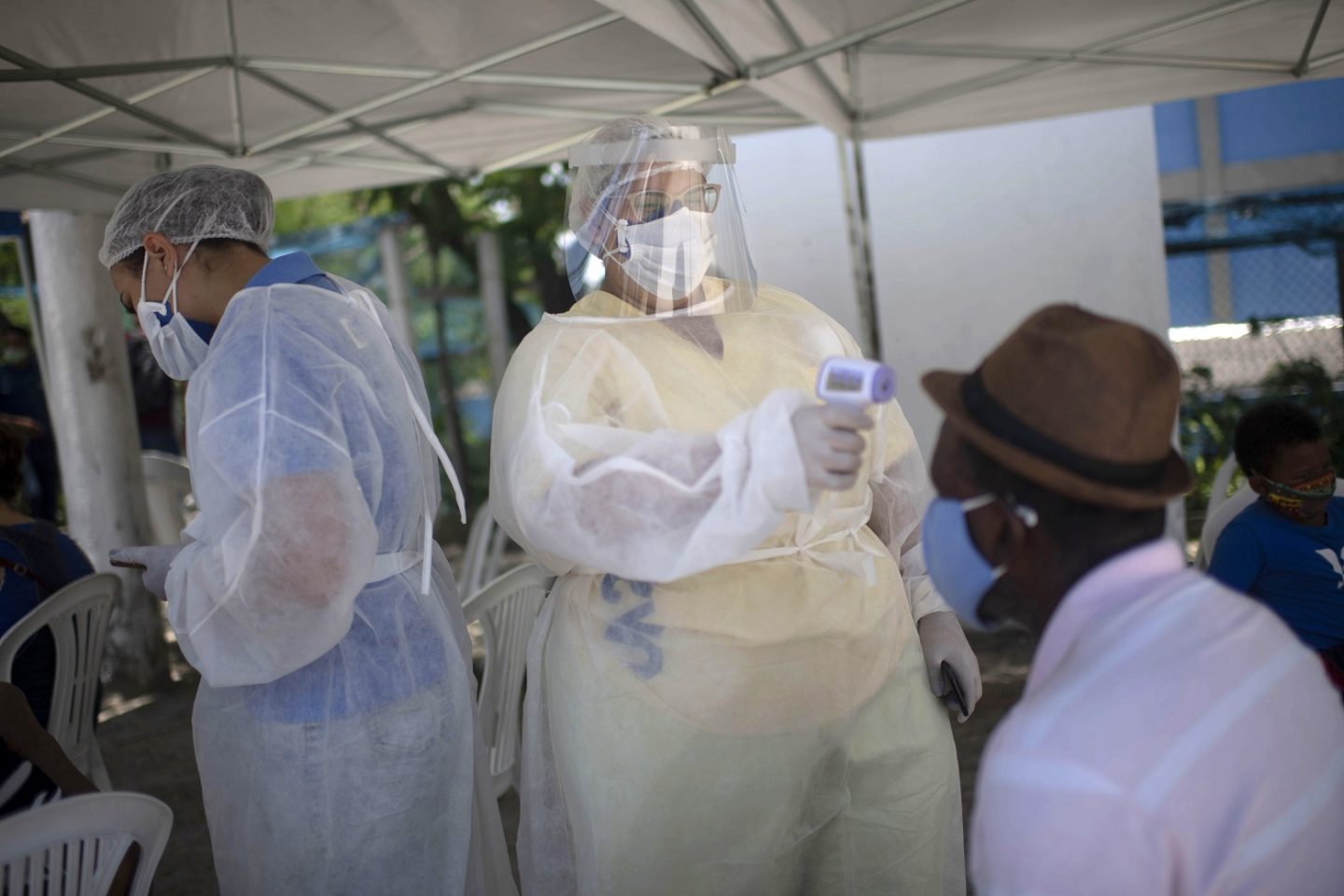 Profissional de saúde mede a temperatura corporal de um homem antes de realizar um teste de PCR para rastreamento de covid-19 em uma unidade de saúde pública em São Gonçalo. Foto Mauro Pimentel/AFP. Dezembro de 2020