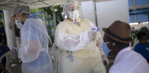 Profissional de saúde mede a temperatura corporal de um homem antes de realizar um teste de PCR para rastreamento de covid-19 em uma unidade de saúde pública em São Gonçalo. Foto Mauro Pimentel/AFP. Dezembro de 2020