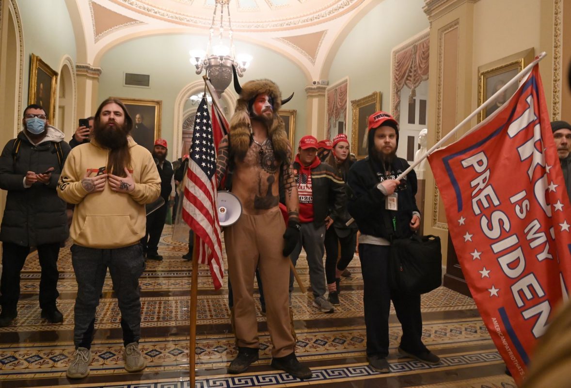 Manifestantes pró-Trump - incluindo Jake A, conhecido como Yellowstone Wolf (centro), membro do grupo de conspiração QAnon - invadem o Congresso dos EUA: pelo menos, quatro mortos e um cerco inédito ao Parlamento (Foto; Saul Loeb / AFP)