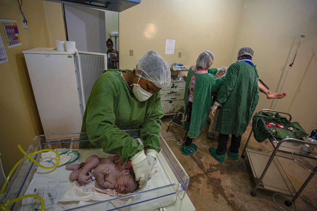 Bebê é atendido em hospital da Ilha de Marajó, no Pará, enquanto profissionais de saúde cuidam de mãe com covid-19: Brasil registrou queda da natalidade em 2020 (Foto: Tarso Sarraf / AFP - 13/06/2020)