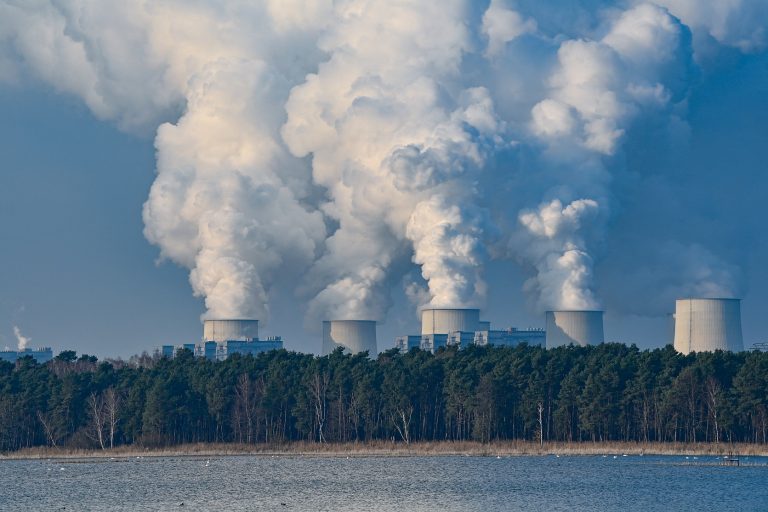 Atrás de um lago, na Alemanha, o vapor sobe das torres de resfriamento da usina movida a lignito, espécie de carvão mineral. O governo alemão promete desativar a usina até 2028. Foto Patrick Pleul/DPA/AFP. Dezembro/2020