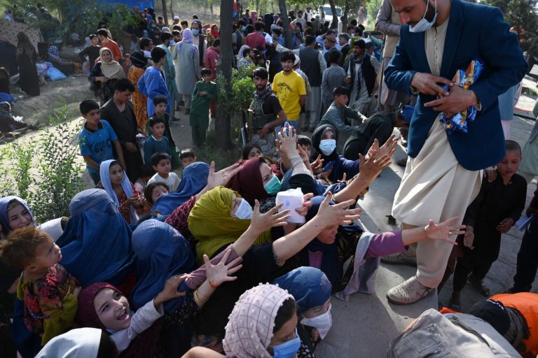 Distribuição de comida em Cabul para refugiados que deixaram suas casas para fugir do avanço do Talibã, uma semana antes da chegada dos guerrilheiros à capital do Afeganistão: mulheres e crianças são a grande maioria entre os 550 mil desalojados (Foto: Wakil Kohsar / AFP - 09/08/2021)