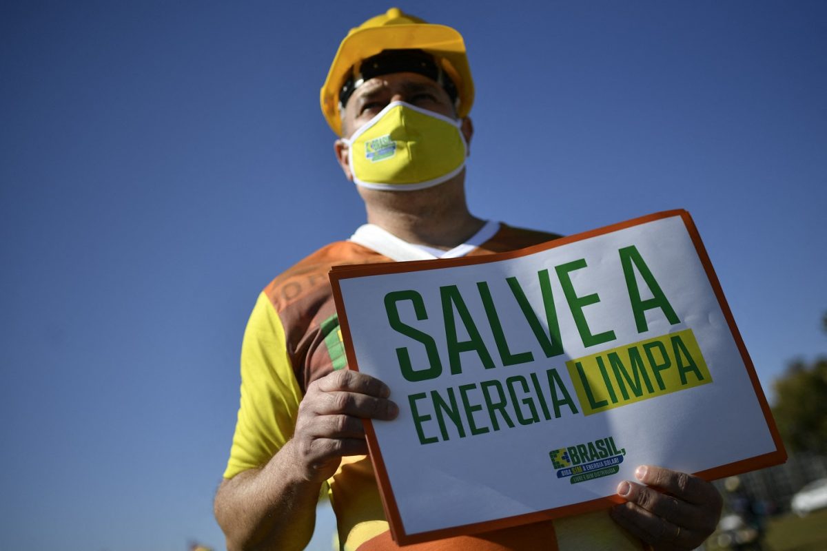 Manifestante segura um cartaz durante uma manifestação em Brasília como parte do movimento "Diga Sim à energia solar". Foto Mateus Bonomi/AGIF/AFP. Junho/2021
