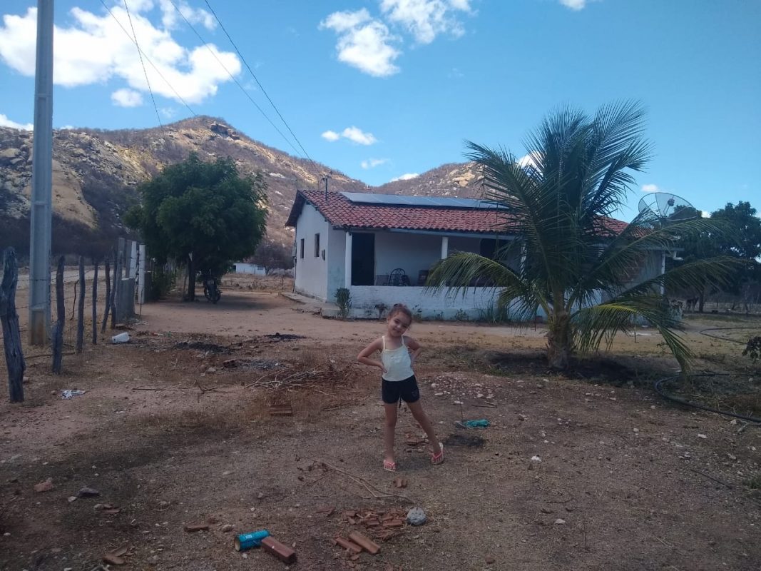 Maria Sophia, neta do assentado Antônio Hermínio, e as placas solares de sua casa no assentamento Novo Horizonte, na zona rural de Várzea, na Paraíba.: transição energética (Foto: Arquivo pessoal)
