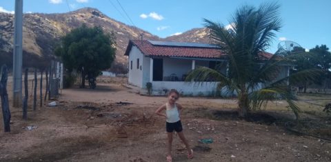 Maria Sophia, neta do assentado Antônio Hermínio, e as placas solares de sua casa no assentamento Novo Horizonte, na zona rural de Várzea, na Paraíba.: transição energética (Foto: Arquivo pessoal)