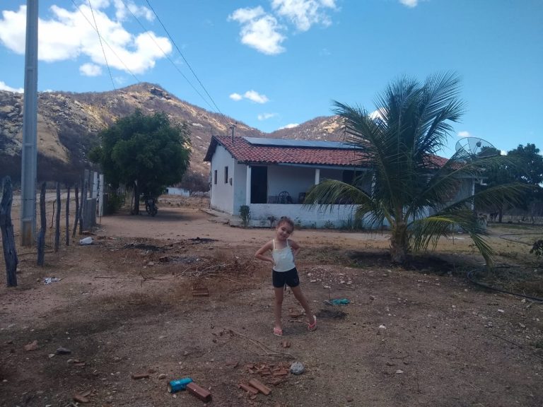 Maria Sophia, neta do assentado Antônio Hermínio, e as placas solares de sua casa no assentamento Novo Horizonte, na zona rural de Várzea, na Paraíba.: transição energética (Foto: Arquivo pessoal)