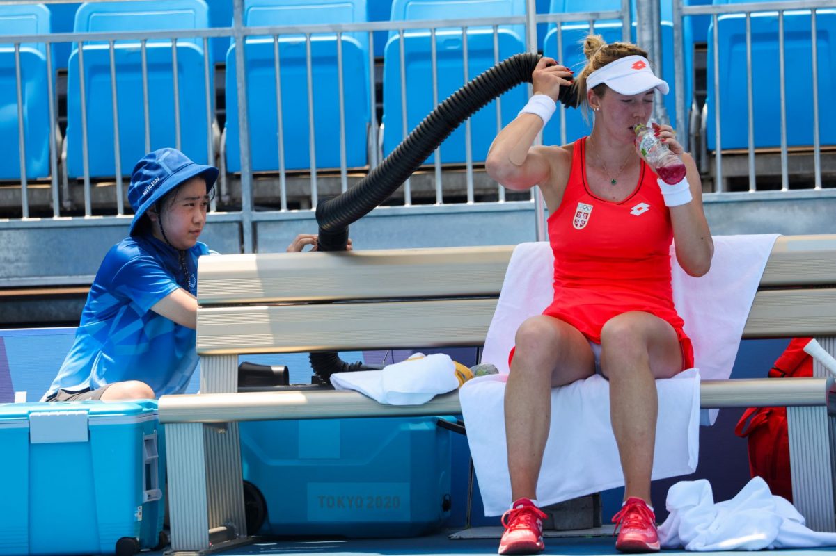 Uma suada voluntária ajuda a tenista sérvia Nina Stojanovic a se refrescar com um ar condicionado durante partida em Tóquio temperaturas sempre acima dos 30 graus apontam para os Jogos Olímpicos mais quentes da história (Giuseppe Cacace /AFP - 24/07/2021)