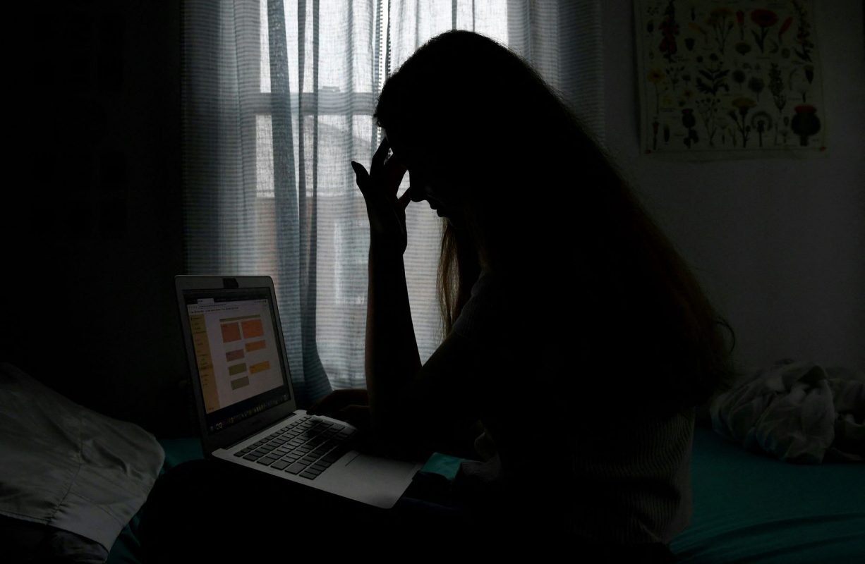Adolescente debruçada sobre laptop: pesquisa mostra que muitos jovens, que pensam sobre suicídio, se sentem mais acolhidos online do que por amigos, parentes e até profissionais de saúde (Foto: Olivier Douliery / AFP - 11/06/2021)