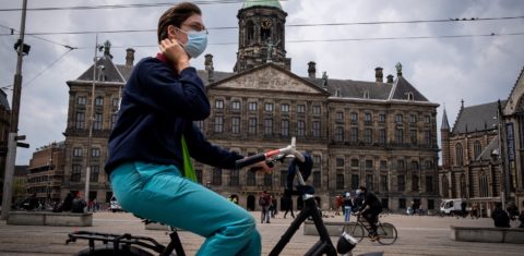 Jovem passeia de bicicleta por Amsterdam, na Holanda. O país voltou a sofrer com a pandemia. Foto Matin Bertrand