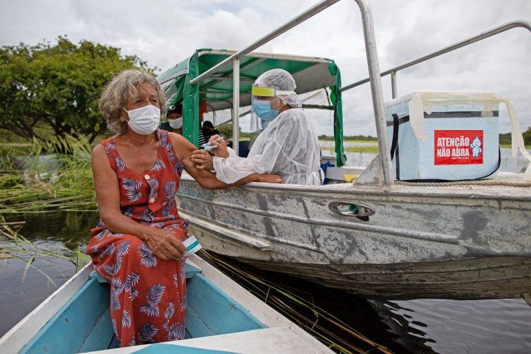 Olga D'arc Pimentel, de 72 anos, é vacinada por um profissional de saúde com uma dose da vacina Oxford-AstraZeneca na comunidade Nossa Senhora do Livramento às margens do Rio Negro perto de Manaus. Foto Michael Dantas/AFP