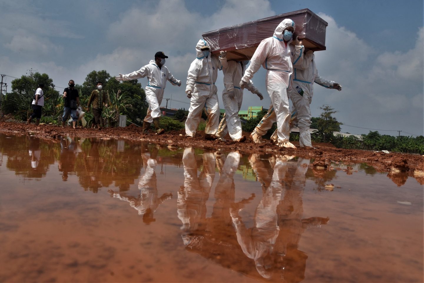 Coveiros carregam o caixão de uma vítima que morreu de covid-19 para ser enterrada em um cemitério em Bekasi, na Indonésia. Foto Rezas/AFP. Agosto/2021