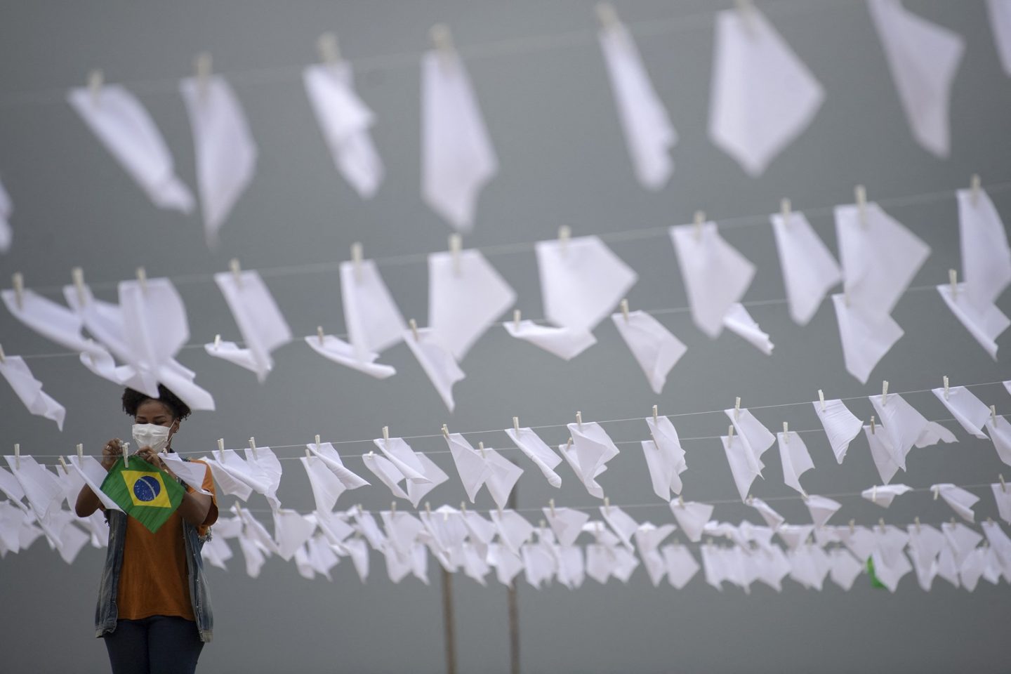 Em Copacabana, ativista do movimento Rio de Paz pendura bandeiras brancas simbolizando a morte de 600 mil brasileiros pela covid-19. Foto Mauro Pimentel/AFP. Outubro/2021