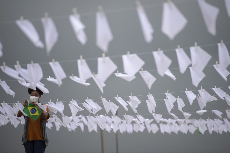 Em Copacabana, ativista do movimento Rio de Paz pendura bandeiras brancas simbolizando a morte de 600 mil brasileiros pela covid-19. Foto Mauro Pimentel/AFP. Outubro/2021