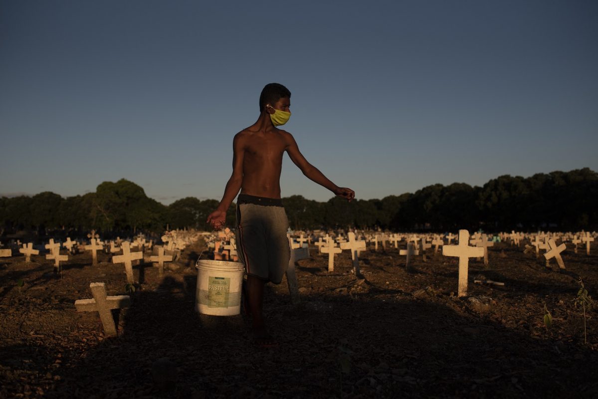 Jovem trabalha em um cemitério do Rio, limpando túmulos e pintando cruzes. Demanda cresceu com a pandemia, que tirou a vida de mais de 605 mil brasileiros. Foto Fabio Teixeira/Anadolu Agency/AFP. Outubro/2021