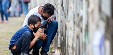 No cemitério Vila Formosa, em São Paulo, Brasil, pai e filho oram pela perda de um parente para a covid-19. Brasil superou a marca de 609 mil mortos para a doença. Foto Paulo Lopes/Anadolu Agency via AFP