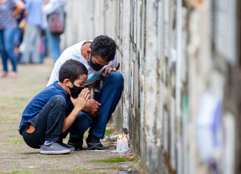 No cemitério Vila Formosa, em São Paulo, Brasil, pai e filho oram pela perda de um parente para a covid-19. Brasil superou a marca de 609 mil mortos para a doença. Foto Paulo Lopes/Anadolu Agency via AFP