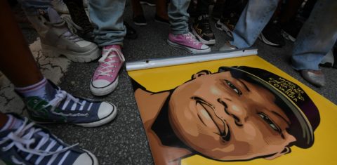 Amigos se reúnem em torno de um cartaz durante um protesto contra o assassinato do refugiado congolês de 24 anos Moise Kabagambe. Foto Nelson Almeida/AFP