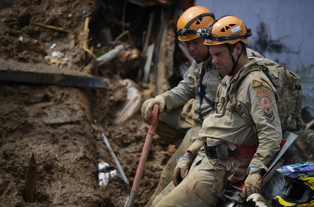 Bombeiros procuram sobreviventes entre os escombros de casas no Morro da Oficina, em Petrópolis. Foto Carl de Souza/AFP
