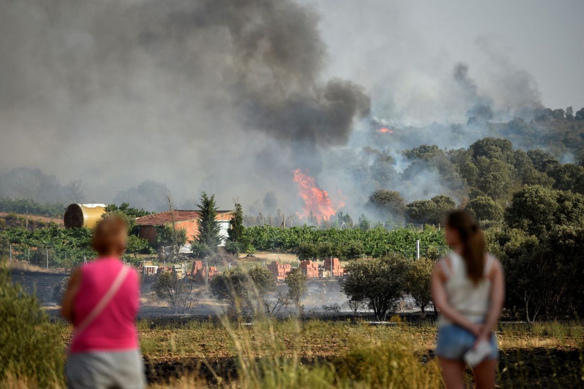 Espanholas observam incêndio florestal que ameaça casas no sudoeste do país: especialistas alertam que onda de calor é só o começo do agravamento da crise climática (Foto: Miguel Rioja / AFP)