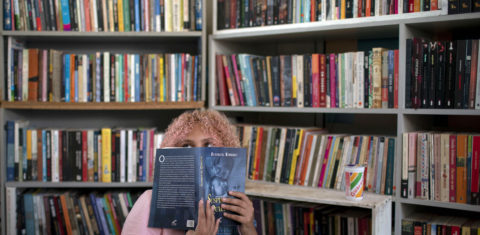 A jovem Lua Oliveira, de 12 anos, espia por trás de um livro na biblioteca pública Mundo da Lua, fundada por ela na favela dos Tabajaras, no Rio de Janeiro. Um bom exemplo de resistência. Foto Mauro Pimentel/AFP