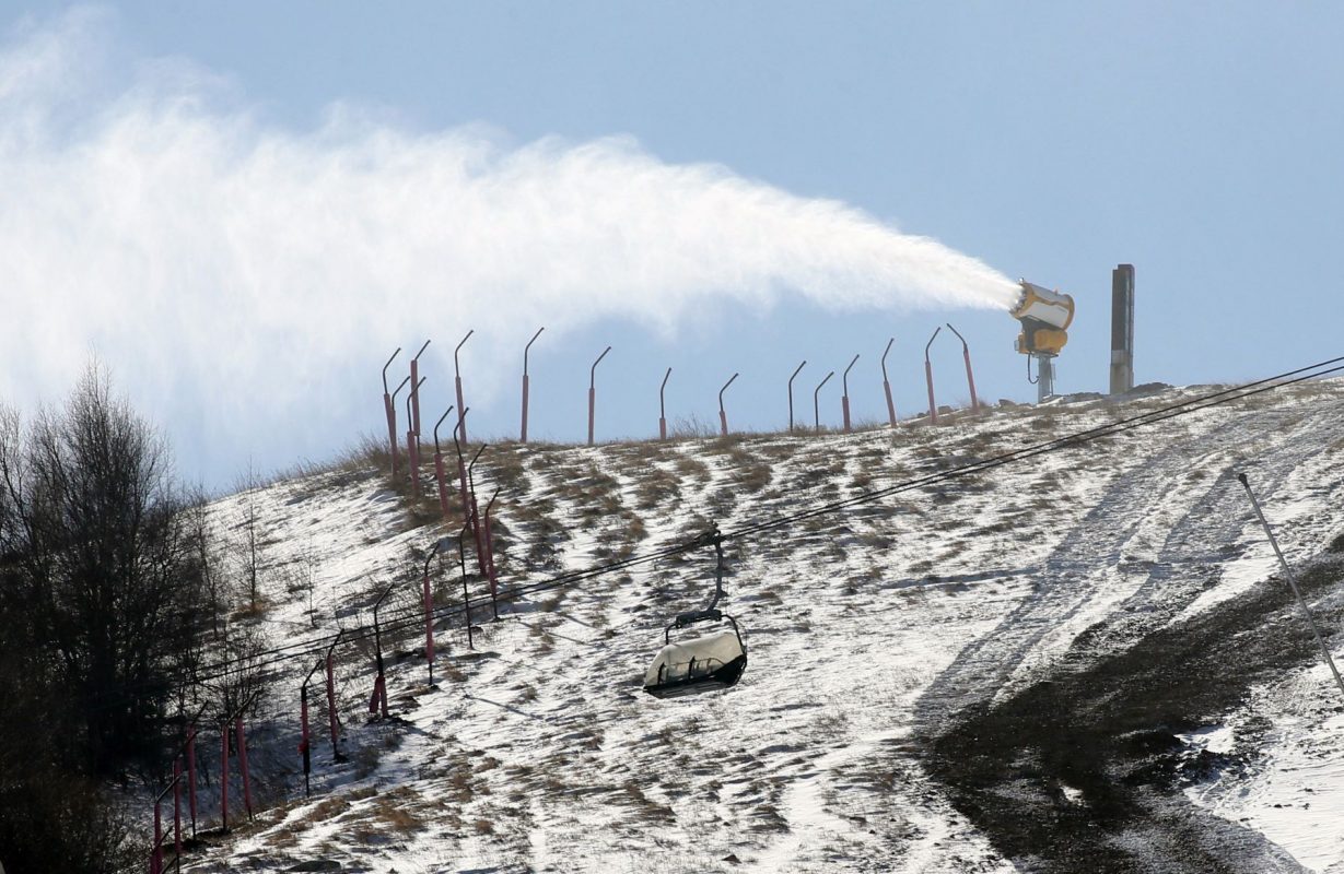 Neve artificial disparada para cobrir colina em Zhangjiakou, cidade chinesa que compartilha com Pequim a sede dos Jogos Olímpicos de Inverno: média de temperatura acima de zero vem obrigando uso de alternativas para manter temporada de esqui (Foto: Koki Kataoka / AFP / 07/12/2021)