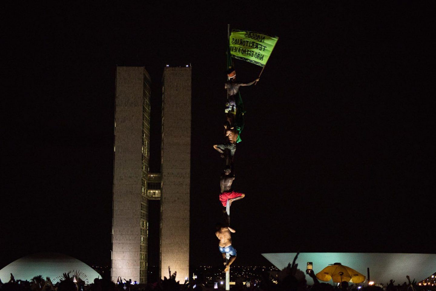 Indígenas levam bandeira com a inscrição "Nossas terras não estão à venda em protesto na Praça dos Três Poderes: sem nada para comemorar no Dia do Índio (Foto: Matheus Alves / Apib)