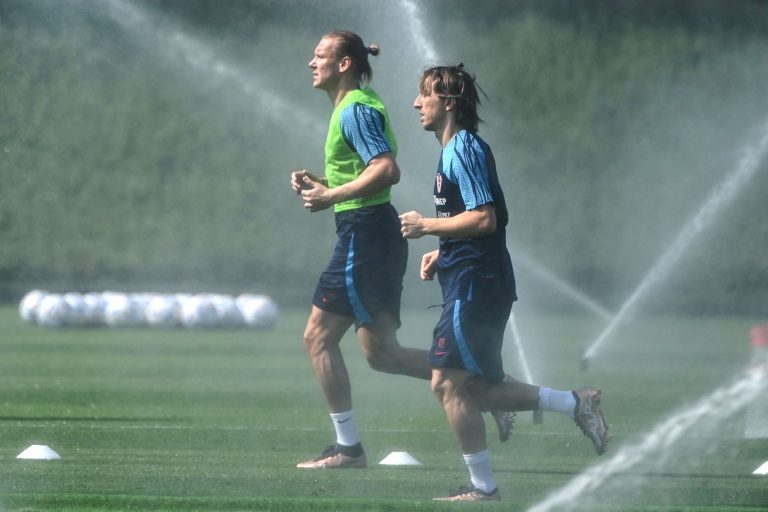 O craque croata Modric e o zagueiro Vida treinam com a irrigação do gramado ligado para amenizar o calor: temperaturas no Catar estão em média 3º C mais altas do que o normal para o período (Foto: Ozam Kode / AFP - 19/11/2022)