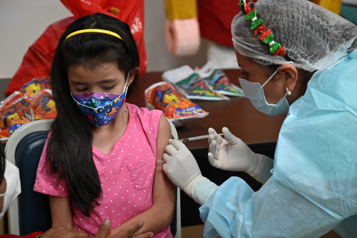 Menina boliviana recebe a primeira dose da vacina da Pfizer contra a covid-19. Foto Aizar Raldez/AFP