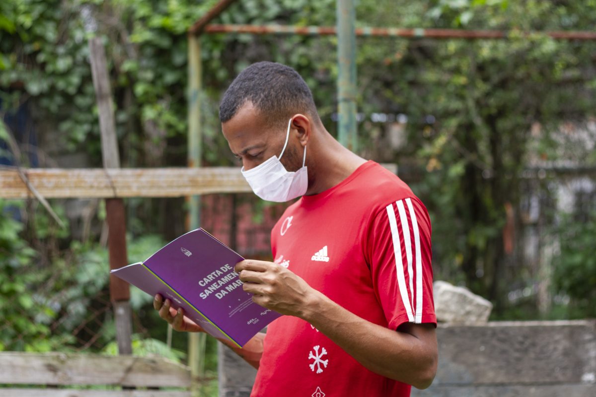 Morador com a carta de saneamento da Maré, publicação que reúne dados do Cocôzap. Foto Patrick Marinho/Data Labe