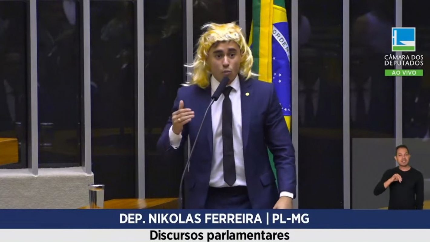 O deputado Nikolas Ferreira discursa de peruca na Câmara: transfobia é crime e ele será processado (Foto: Reprodução / TV Câmara)