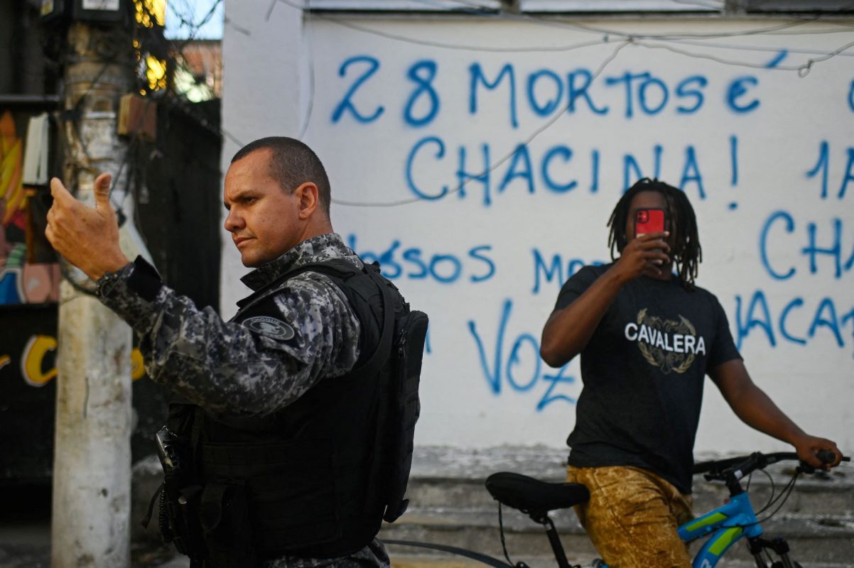 Morador filme a ação da polícia durante um protesto contra a ação policial na favela do Jacarezinho, no Rio. Foto André Borges/AFP