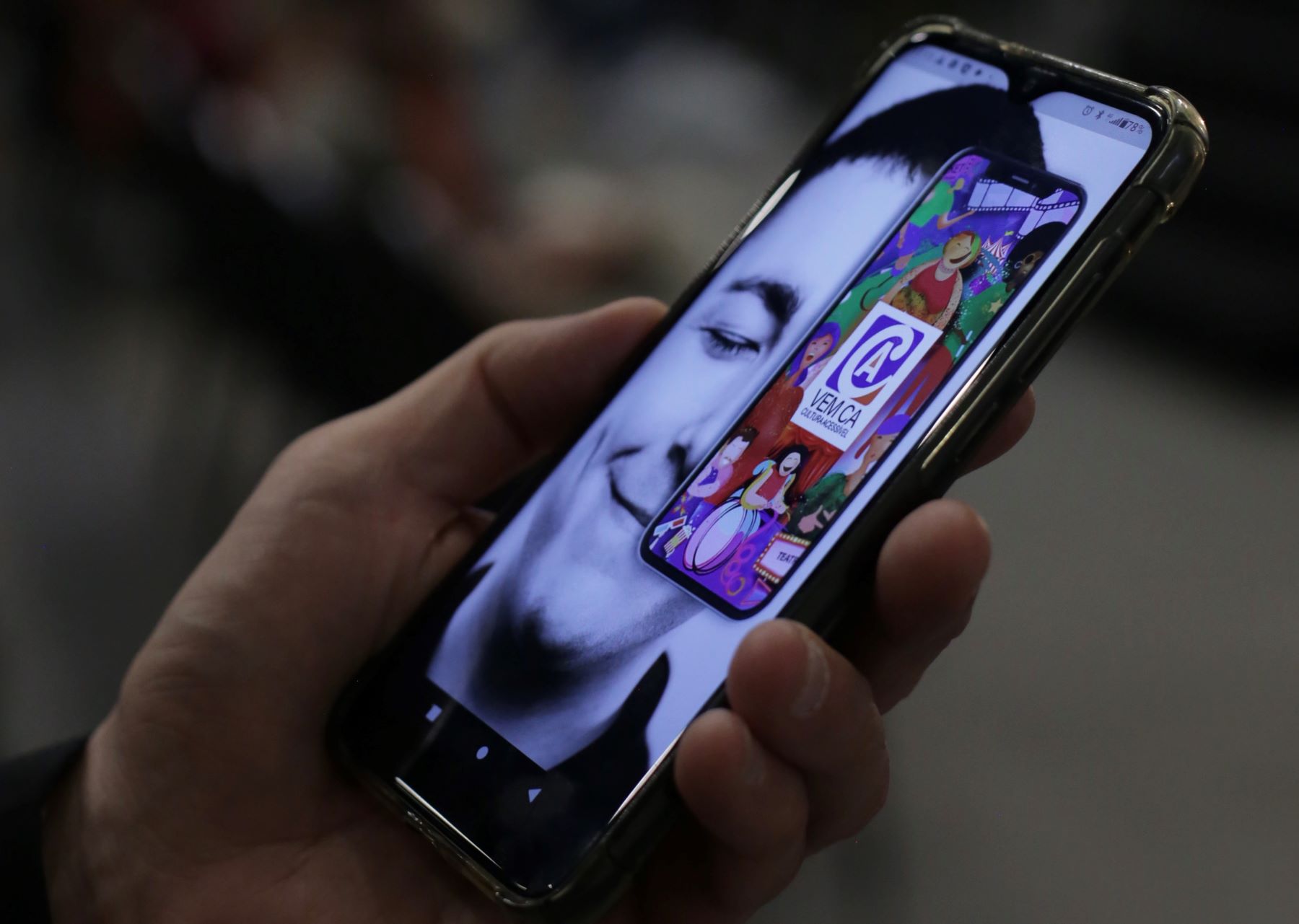 Fotografia mostrando mão segurando celular, que está com a tela inicial do aplicativo Vem Cá aberta