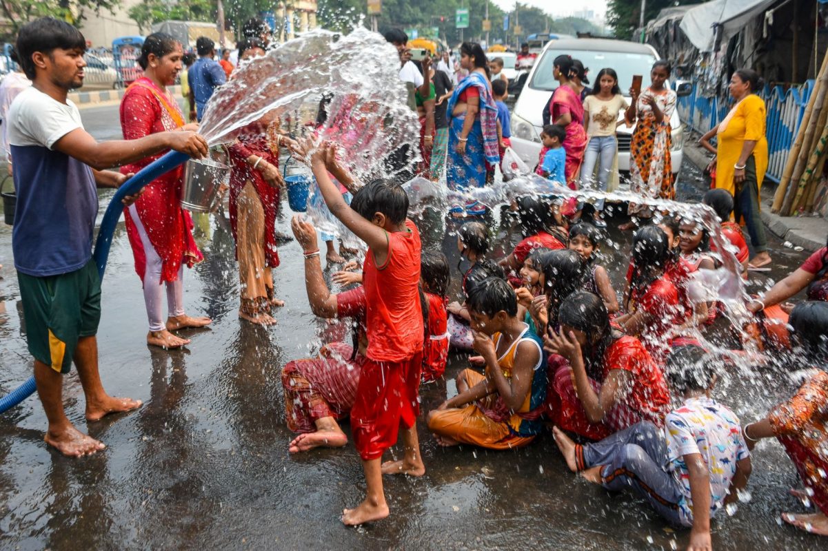Crianças e adultos aproveitam água de carro-pipa para tomar banho e encher vasilhas em Kolkata, na Índia: onda de calor no abril mais quente da história na Ásia (Foto: Debarchan Chatterjee / NurPhoto / AFP - 15/04/2023)