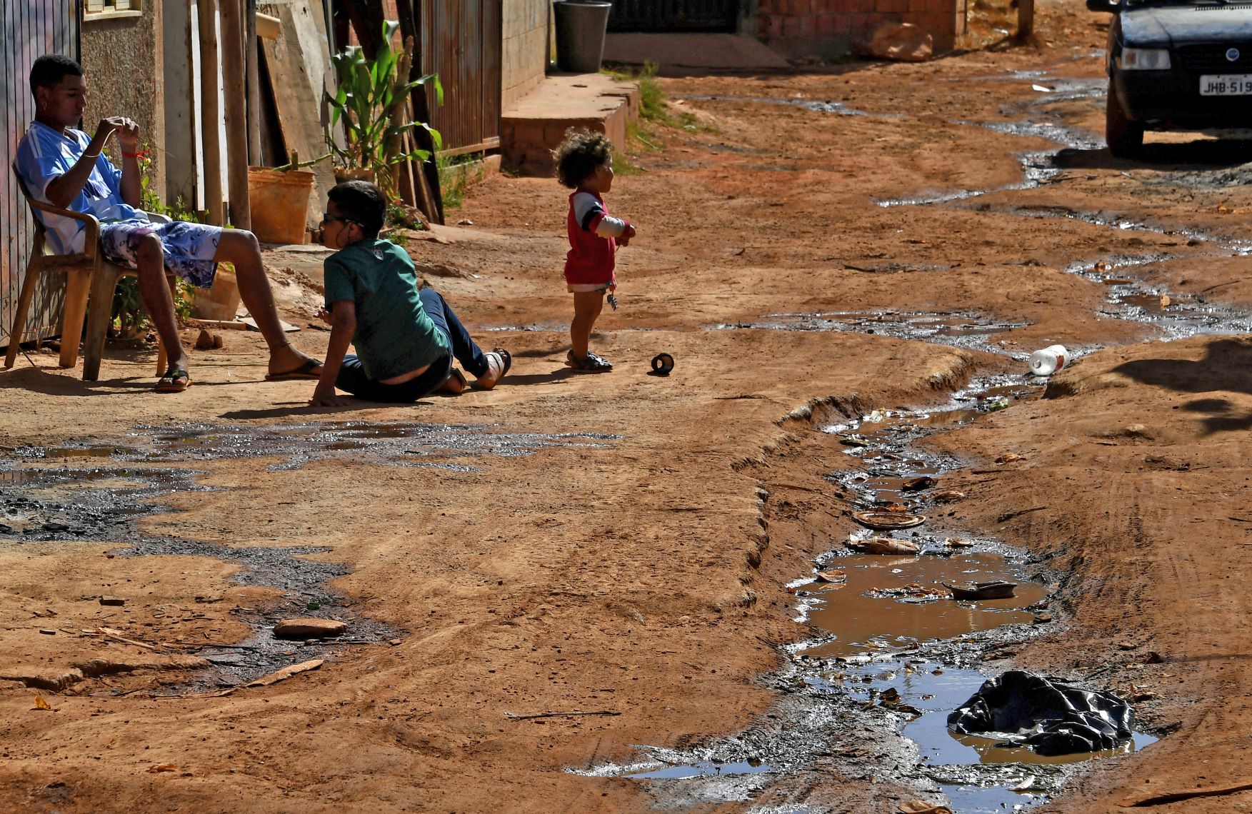 Criança brinca ao lado de vala de esgoto na periferia do Distrito Federal: Brasil tem 35 milhões sem acesso à água potável e quase 100 milhões sem coleta de esgoto (Foto; Evaristo Sá / AFP - 04/08/2023)
