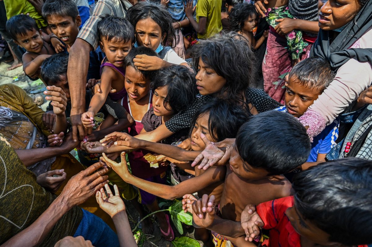 Refugiados Rohingya recém-chegados recebem alimentos doados por pessoas em uma praia em Laweueng, distrito de Pidie, na província indonésia de Aceh. Foto Chaideer Mahyussin/AFP