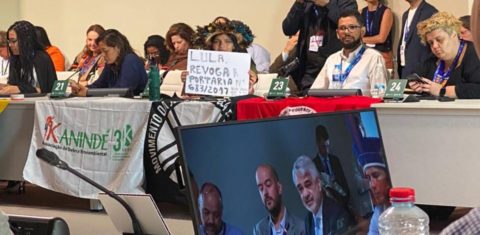 Em reunião com o presidente na COP28, em Dubai, Txai Paiter Suruí segura uma placa pedindo providências do governo. Foto Raylson Santos