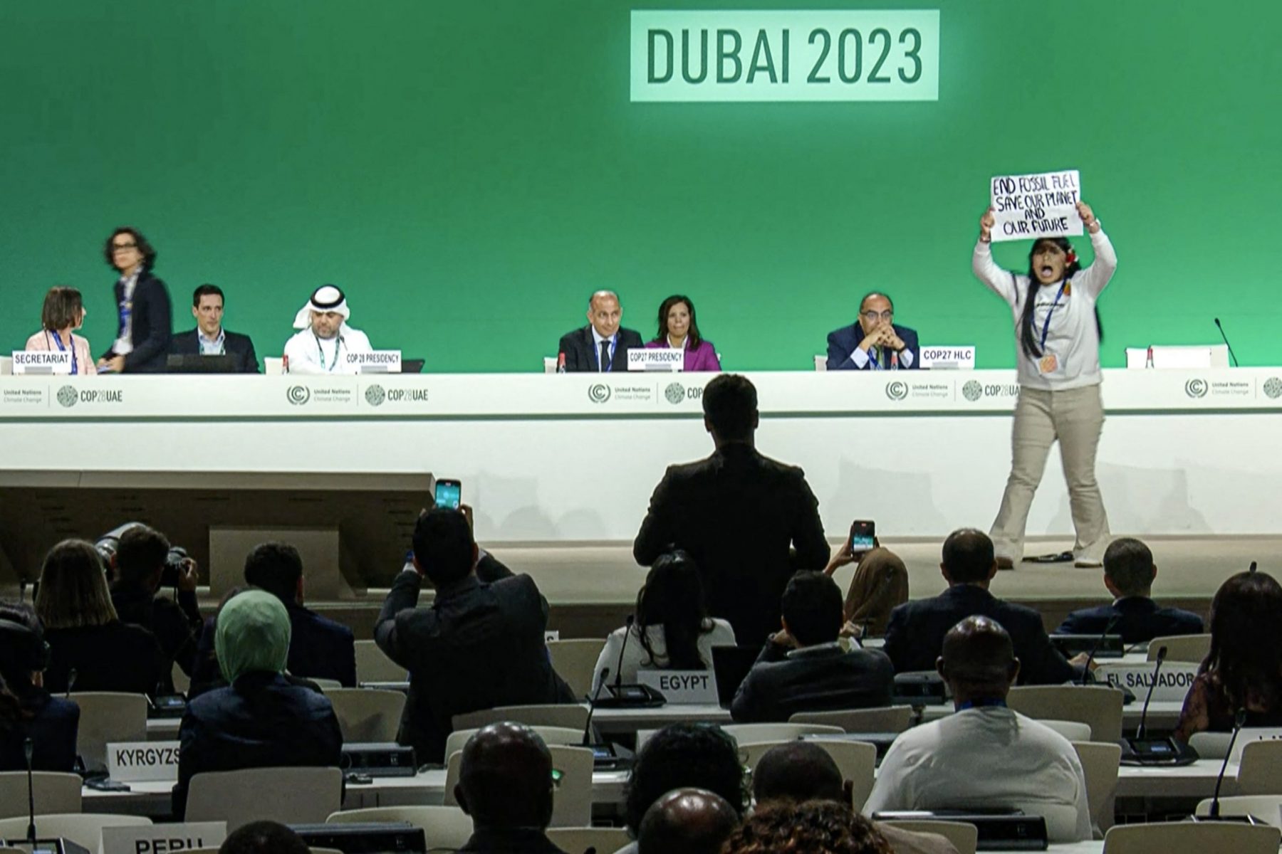 Ativista sobe ao palco da COP28, em Dubai, para protestar contra a produção e consumo de combustíveis fósseis. Foto AFPTV/AFP