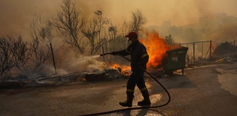 Na onda de calor que atinge a Europa, bombeiro combate um incêndio na área urbana do sul de Ática, na Grécia. Foto Giorgos Arapekos/NurPhoto via AFP. Julho/2023