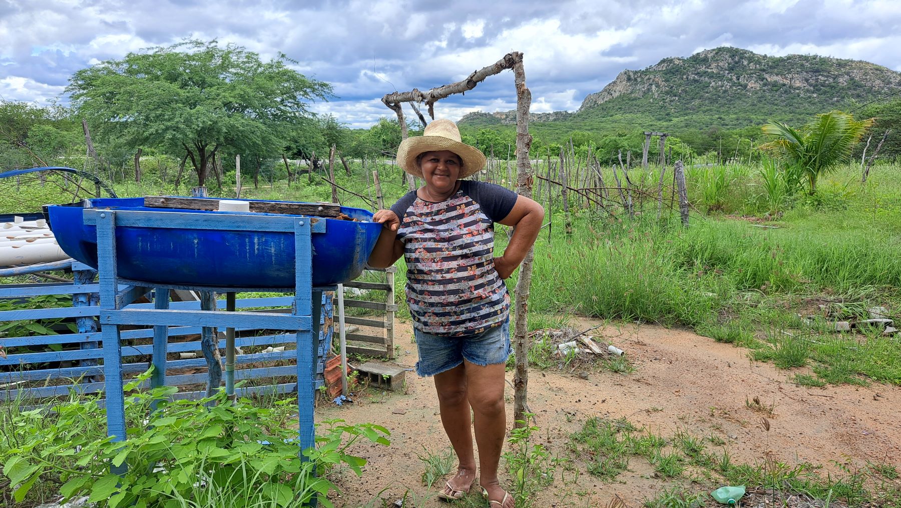 A agricultora Geralda Nery com o que restou de seu sistema agrofotovoltaico, agora sem funcionamento: falta de assistência técnica (Foto: Letícia Barbosa/ Coletivo Caburé)