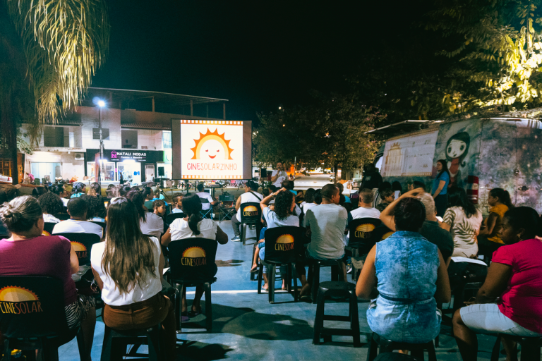 Exibição de filme pelo CineSolar em Belo Oriente (MG): dois furgões com placas fotovoltaicas no teto e sistema conversor de energia para levar cinema ao interior do Brasil (Foto: Pedro Cerqueira / Cine Solar - 20/03/2023)