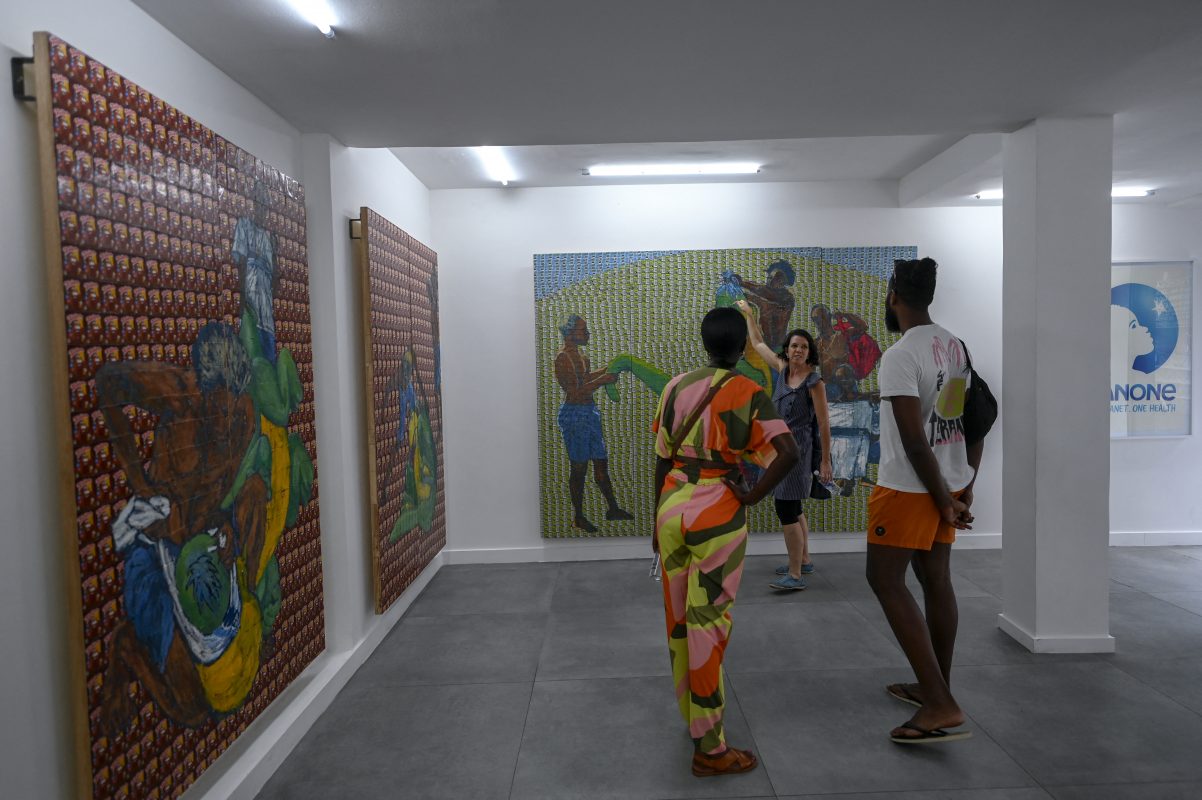 Visitantes apreciam as pinturas do artista Maxwell Alexandre na galeria fundada pelo artista, na favela da Rocinha. Foto Mauro Pimentel/AFP