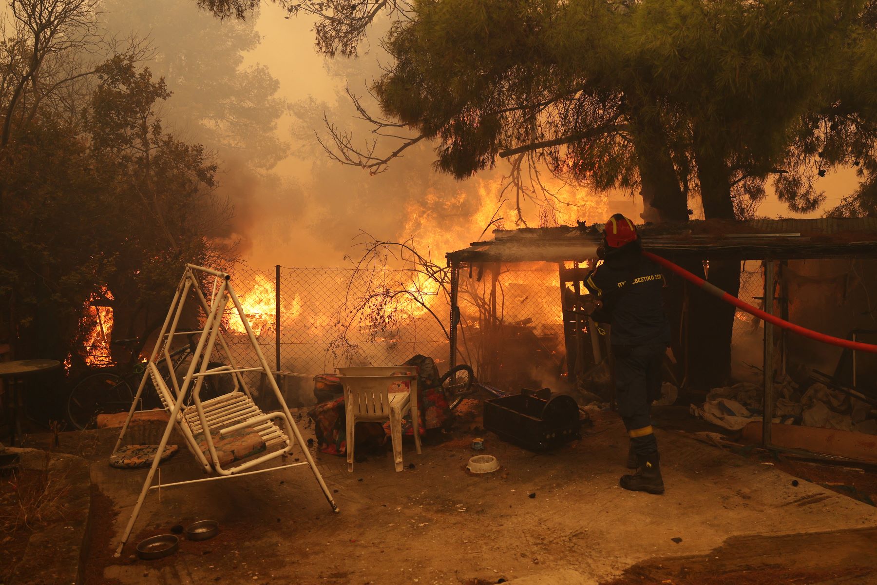 Bombeiro enfrenta incêndio em escola na vila Nea Penteli, perto de Atenas: fogo se alastra com altas temperaturas, seca extrema e ventos (Foto: Costas Baltas / Anadolu / AFP)